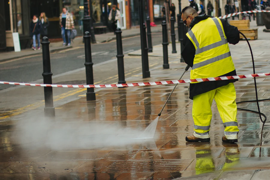 Technician pressure washing grime off paved concrete